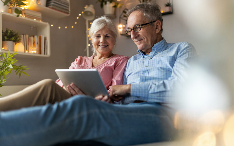Mature couple using a laptop while relaxing at home looking at equity release